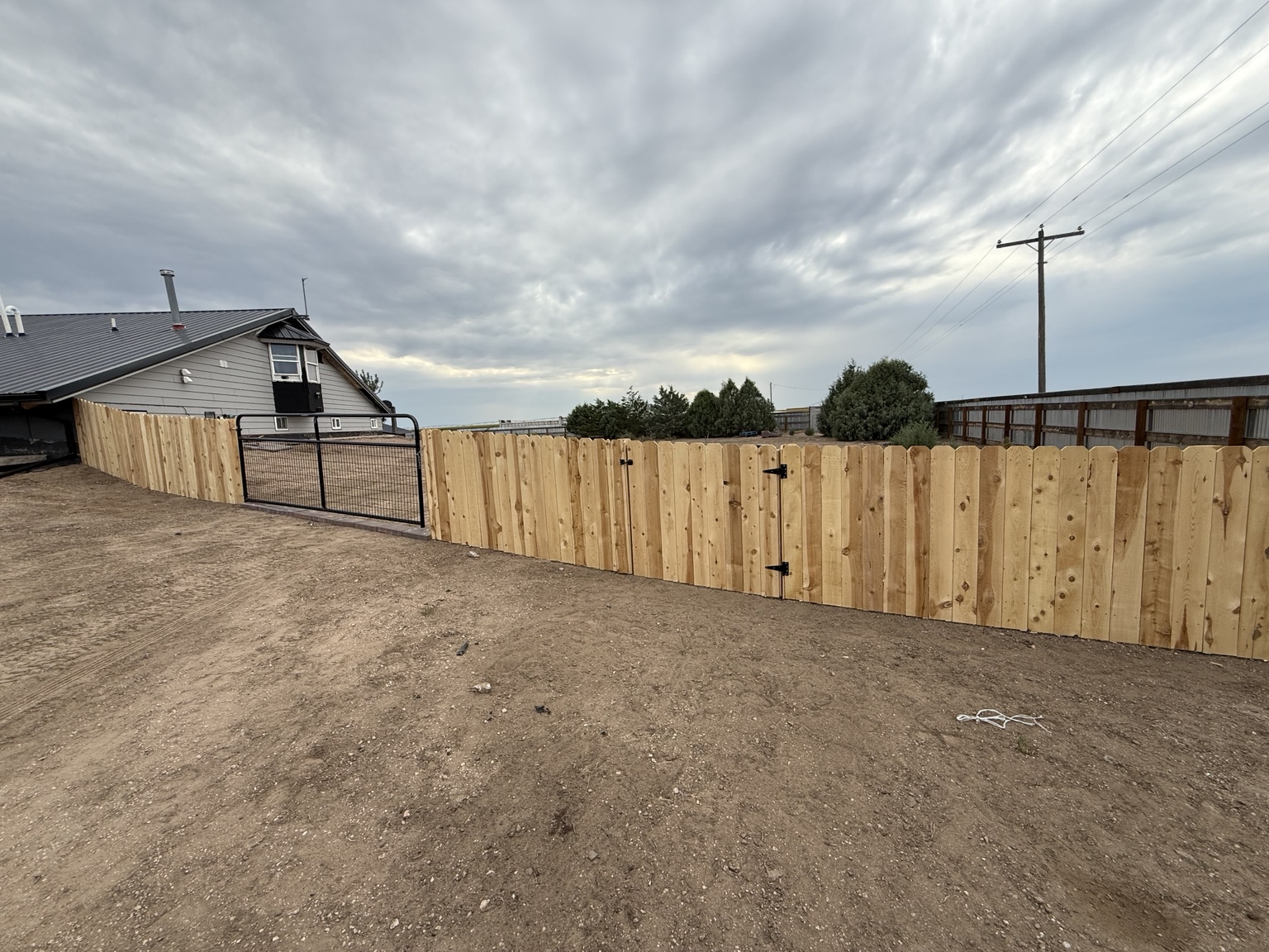Long cedar privacy fence with a black metal gate