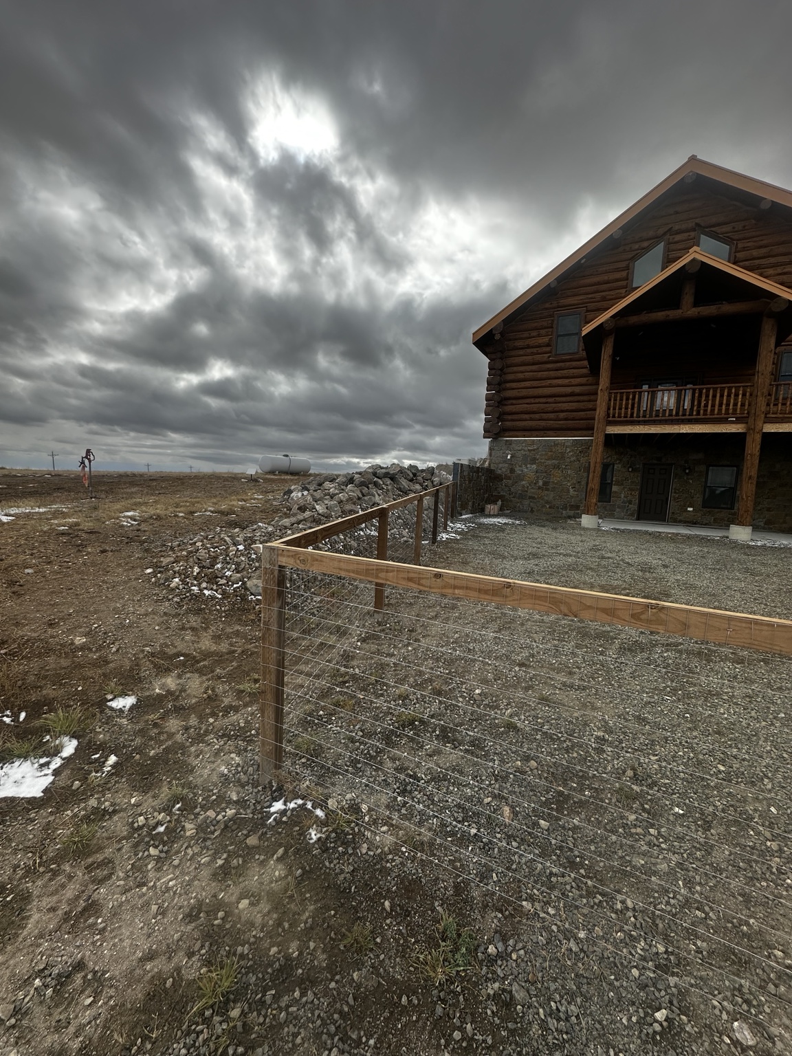 Wire mesh enclosure and gravel area beside a log home