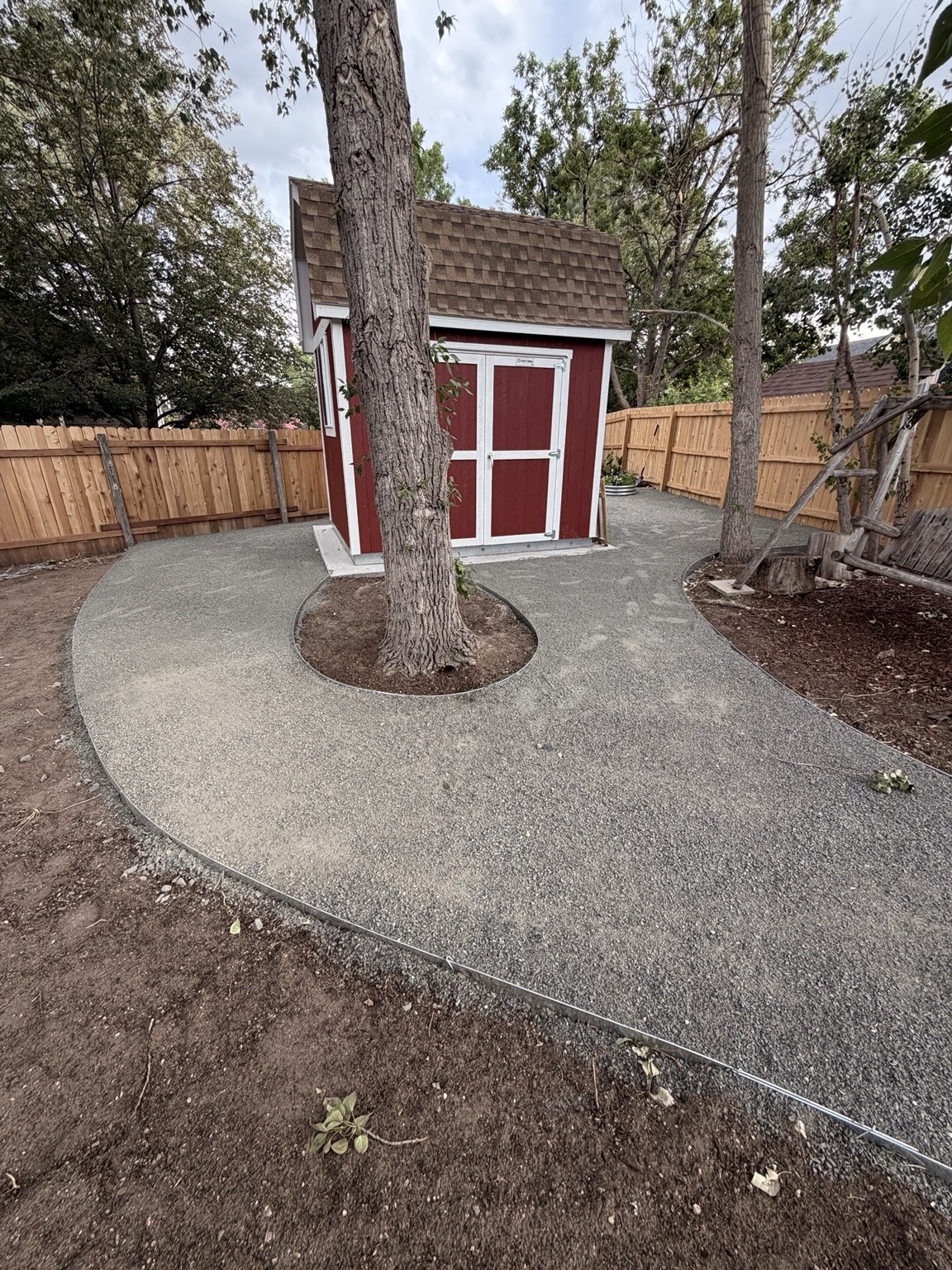 Curved concrete walkway through a landscaped backyard