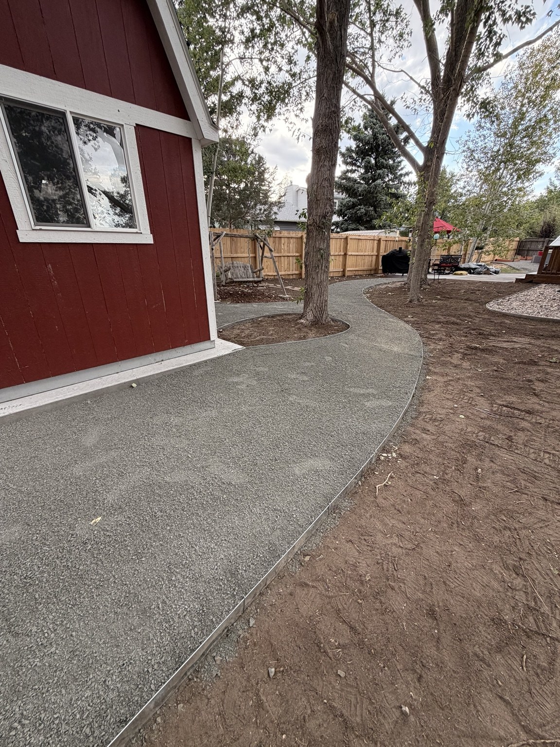 Curved aggregate walkway around a backyard shed