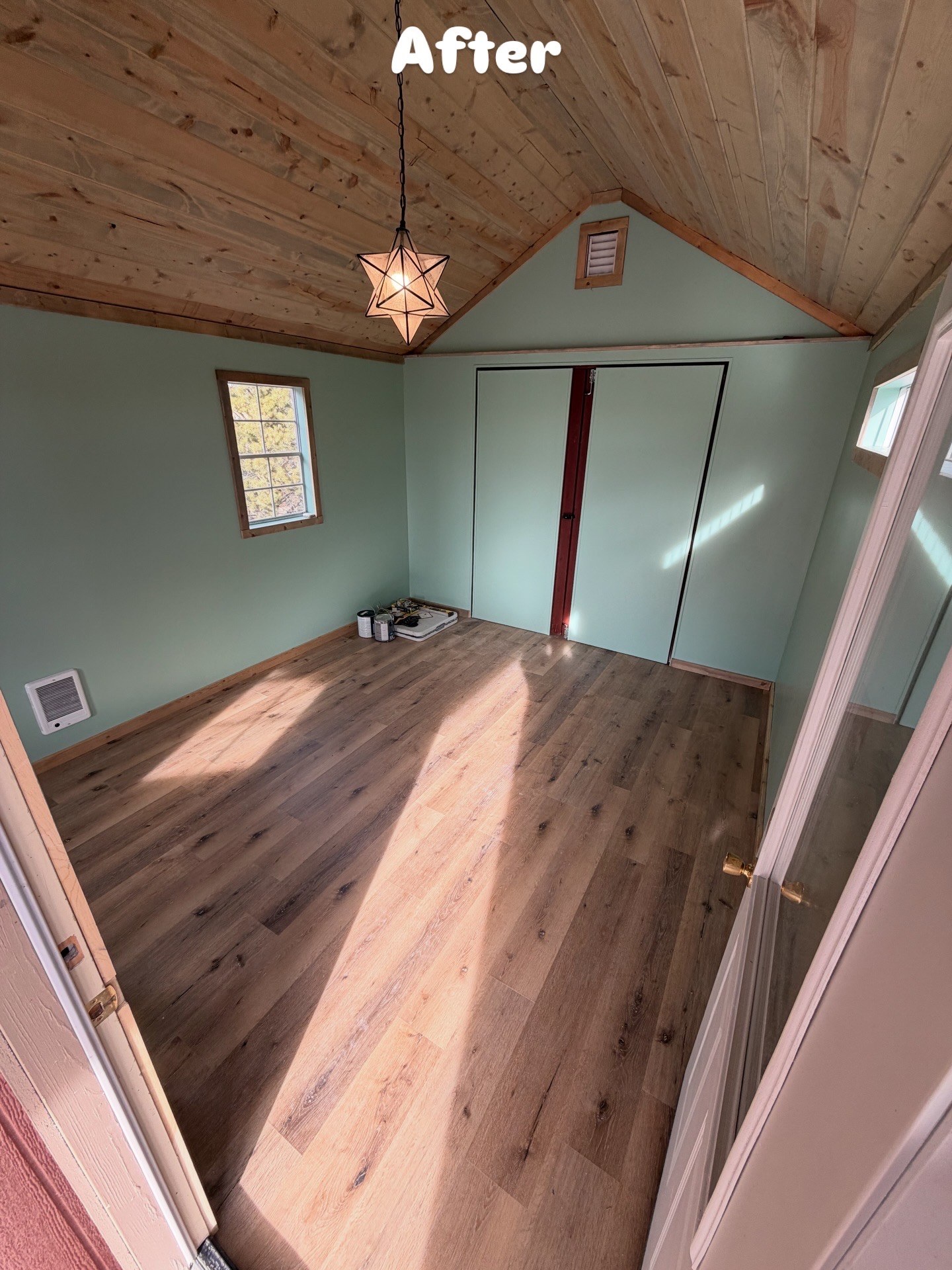 Finished shed with sage-green walls and wood-look LVP flooring