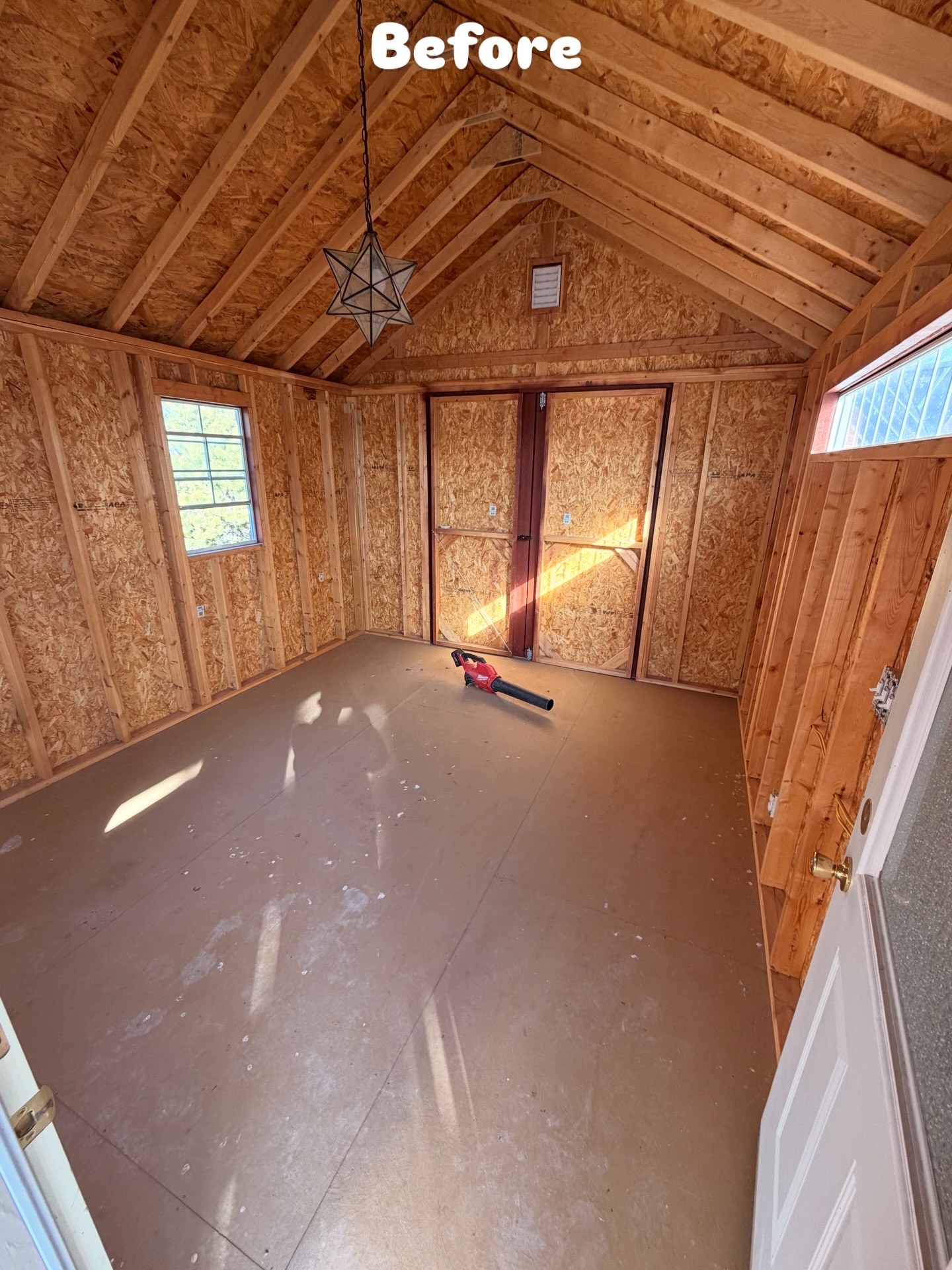 Unfinished shed interior before wall, ceiling, and flooring improvements